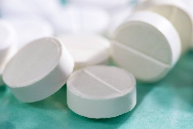 Masaya saçılmış beyaz yuvarlak tabletler, yeşil bir zemin üzerine.