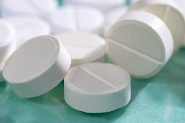 Masaya saçılmış beyaz yuvarlak tabletler, yeşil bir zemin üzerine.