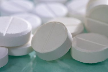 Masaya saçılmış beyaz yuvarlak tabletler, yeşil bir zemin üzerine.