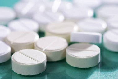 Masaya saçılmış beyaz yuvarlak tabletler, yeşil bir zemin üzerine.