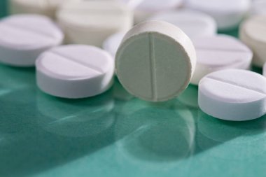 Masaya saçılmış beyaz yuvarlak tabletler, yeşil bir zemin üzerine.