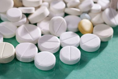 Masaya saçılmış beyaz yuvarlak tabletler, yeşil bir zemin üzerine.