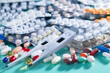 Renkli arka planda termometre ve tıbbi haplar. Yakın plan..