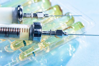 Mavi arka planda ampullü iğneler için tıbbi şırıngalar.