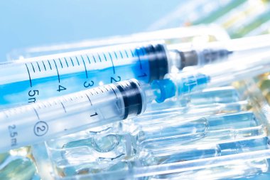 Mavi arka planda ampullü iğneler için tıbbi şırıngalar.