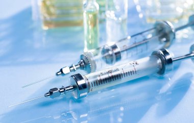 Mavi arka planda ampullü iğneler için tıbbi şırıngalar.