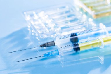 Mavi arka planda ampullü iğneler için tıbbi şırıngalar.