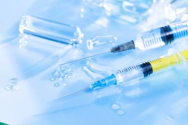 Mavi arka planda ampullü iğneler için tıbbi şırıngalar.