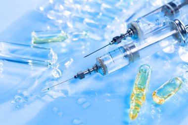 Mavi arka planda ampullü iğneler için tıbbi şırıngalar.