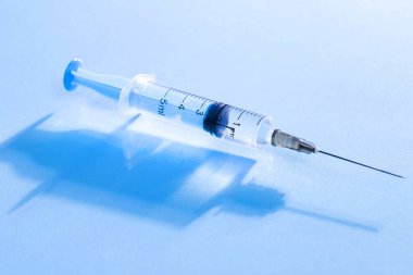 Mavi arka planda enjeksiyon için tıbbi şırınga.