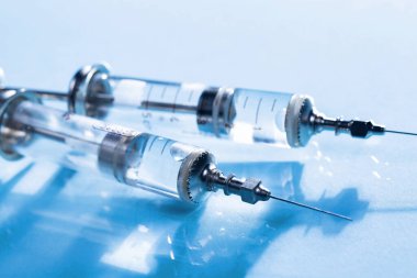 Mavi arka planda ampullü iğneler için tıbbi şırıngalar.