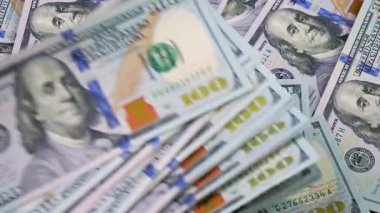 Rastgele düzenlenmiş, yavaşça dönen 100 dolarlık banknotlar. Yukarıdan görüntüle.