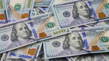 Rastgele düzenlenmiş, yavaşça dönen 100 dolarlık banknotlar. Yukarıdan görüntüle.