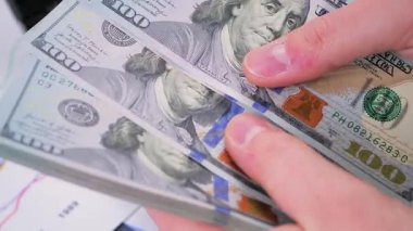 Genç bir muhasebecinin elleri 100 dolarlık banknotları ayırıp sayıyor..