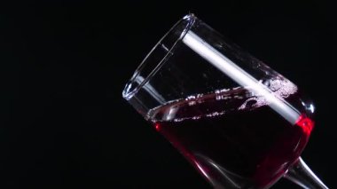 Kırmızı kuru şarap, şişeden bardağa dökülüyor, siyah arka planda. Yakın plan. Yavaş çekim.