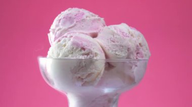 Cam bir vazodaki meyveli dondurma, parlak bir arkaplanda, kendi ekseni etrafında yavaşça döner..