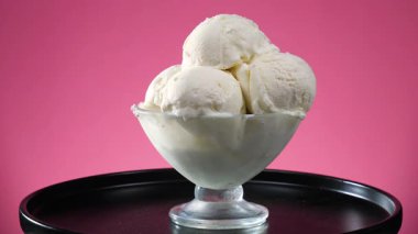 Cam bir vazodaki vanilyalı dondurma, parlak bir arkaplanda, ekseni etrafında yavaşça döner..