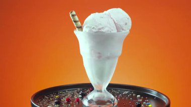 Cam bir vazodaki vanilyalı dondurma, parlak bir arkaplanda, ekseni etrafında yavaşça döner..