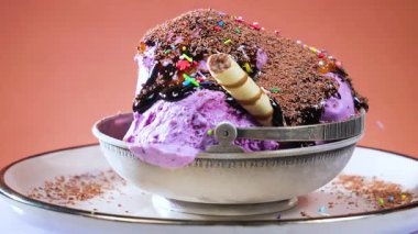 Yenebilir konfeti serpiştirilmiş metal bir kasede meyveli dondurma, parlak bir arka planda yavaşça dönüyor..