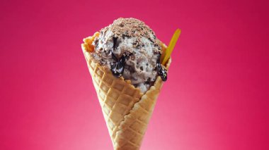 Waffle külahındaki dondurma, parlak bir arkaplanda kendi ekseni etrafında yavaşça döner.