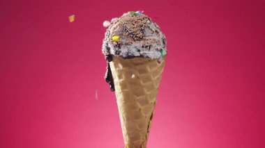 Waffle külahındaki dondurma, parlak bir arkaplanda kendi ekseni etrafında yavaşça döner.