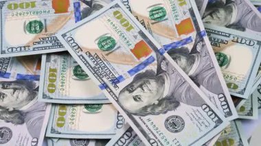 Rastgele düzenlenmiş, yavaşça dönen 100 dolarlık banknotlar. Yukarıdan görüntüle.