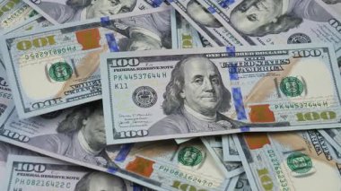 100 dolarlık banknotlar kaotik bir şekilde düzenlenmiş 100 dolarlık banknotların üzerine yavaşça düşer. Yukarıdan görüntüle.