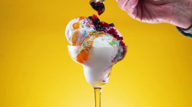 Bardaktaki vanilyalı dondurma böğürtlenli şurupla doldurulur ve yavaşça ekseni etrafında döner.