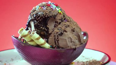 Cam bir kasede çikolatalı dondurma, parlak bir arka planda yavaşça dönüyor.,