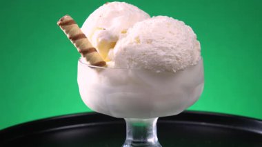 Cam bir vazodaki vanilyalı dondurma, parlak bir arkaplanda, ekseni etrafında yavaşça döner..