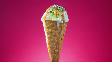 Waffle külahındaki dondurma, parlak bir arkaplanda kendi ekseni etrafında yavaşça döner.