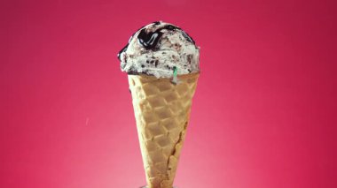 Waffle külahındaki dondurma, parlak bir zemin üzerinde renkli yenilebilir konfeti serpiştirilmiş, kendi ekseni etrafında yavaşça döner.