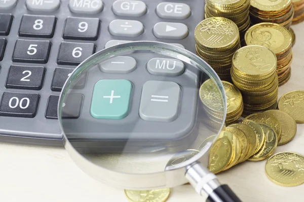Золотые монеты, калькулятор и увеличительное стекло - бизнес-концепция — стоковое фото