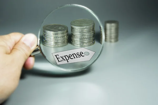 Magnifier, Expense Tag, And Stack Of Coins In The Backdround — Stock Photo, Image