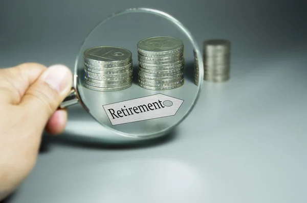 Vergrootglas, pensioen Tag en stapel van munten in de backdround — Stockfoto