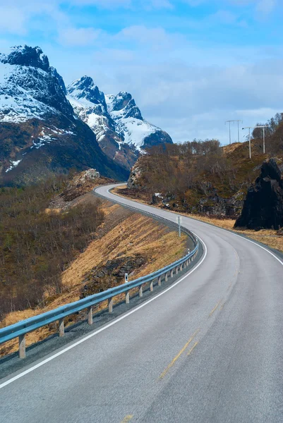 Carretera gris en las montañas noruegas nevadas Imagen de archivo