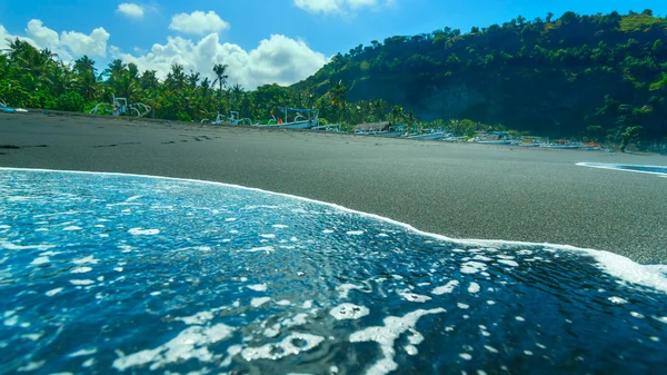 A Bali szigetén, Indone a fekete homokos strandon csónakok — Stock Fotó