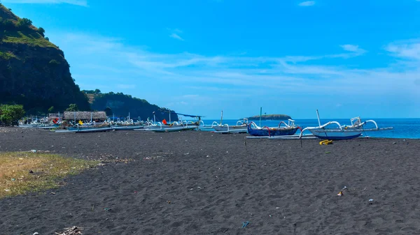 A Bali szigetén, Indone a fekete homokos strandon csónakok — Stock Fotó