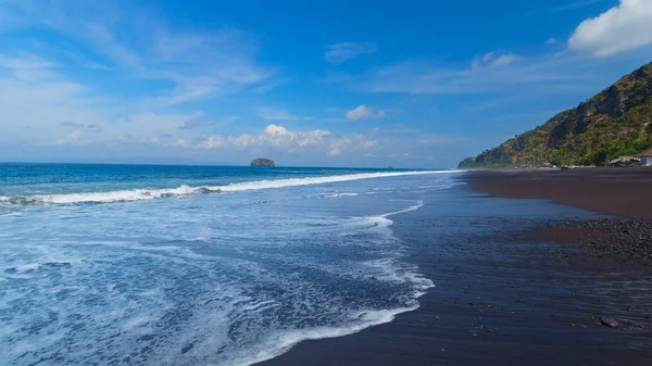 与黑色的火山沙，在印度的巴厘岛海滩 图库图片