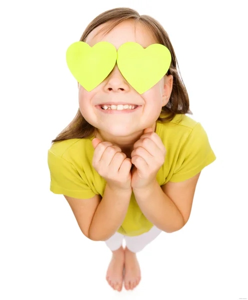 Little girl is holding hearts over her eyes — Stock Photo, Image