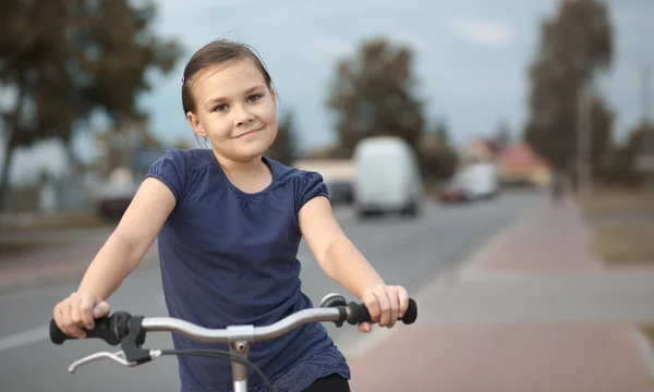 Sevimli kız bisiklet üzerinde oturuyor — Stok fotoğraf