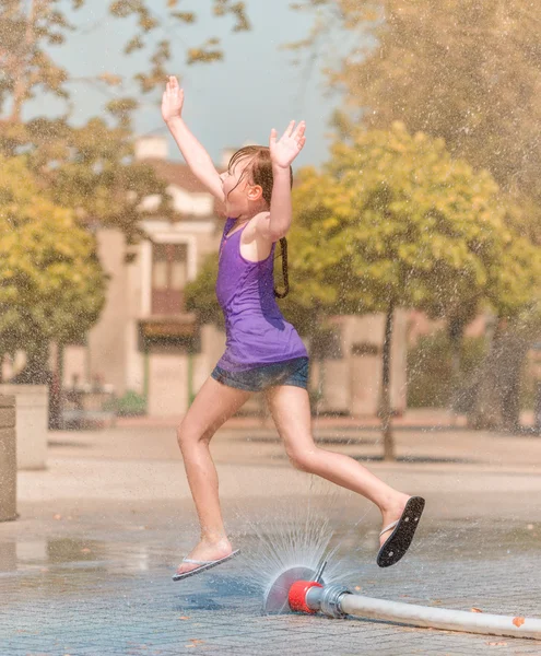 女の子は噴水を通じて実行されます。 — ストック写真