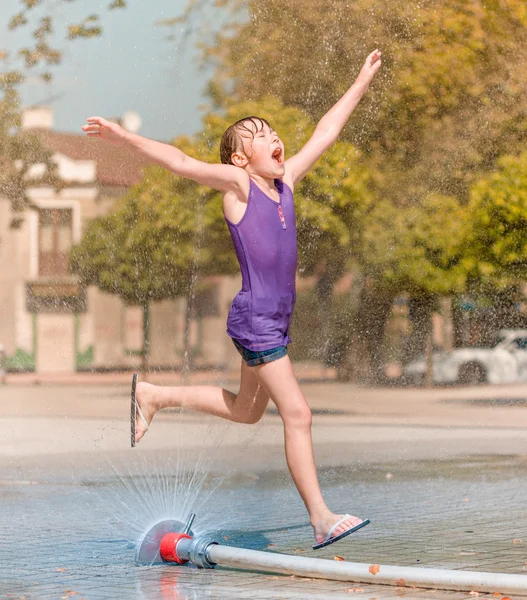 女の子は噴水を通じて実行されます。 — ストック写真