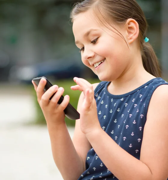 Chica está usando teléfono inteligente Imagen de stock