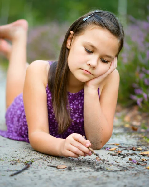 Menina está deitado na estrada da floresta e desenho Fotografias De Stock Royalty-Free