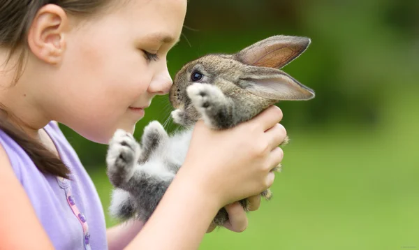Chica está sosteniendo un pequeño conejo Fotos de stock