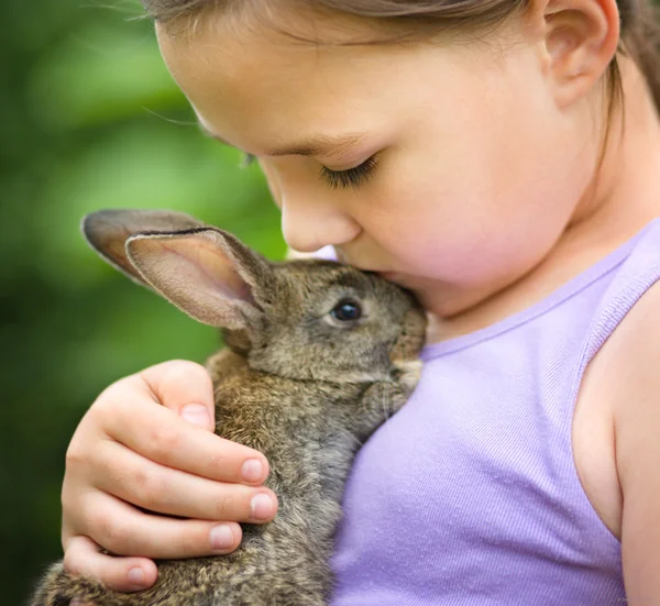 Chica está sosteniendo un pequeño conejo Imagen de archivo