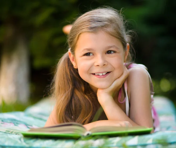 Little girl is reading a book outdoors — Stock Photo, Image