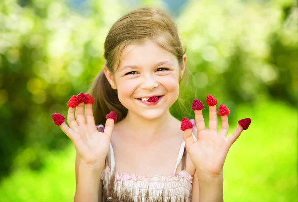Menina está segurando framboesas em seus dedos — Fotografia de Stock