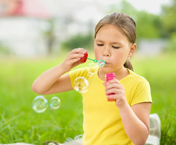 Liten flicka blåser en såpbubblor — Stockfoto